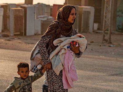 Женщина со своими детьми бежит от турецкой бомбардировки Рас-эль-Айна. Фото: Delil SOULEIMAN / AFP